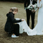 wedding photographer fixing the bride's dress for a photo