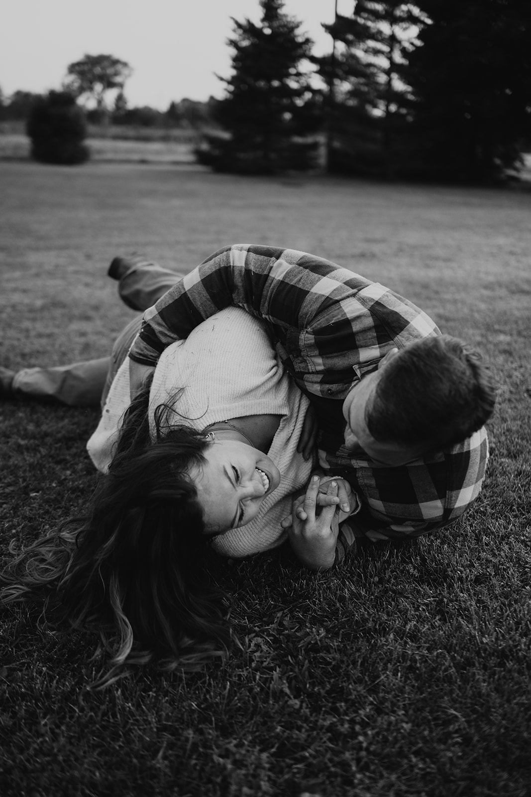 couple pose: couple are playfully rolling on the ground holding each other.