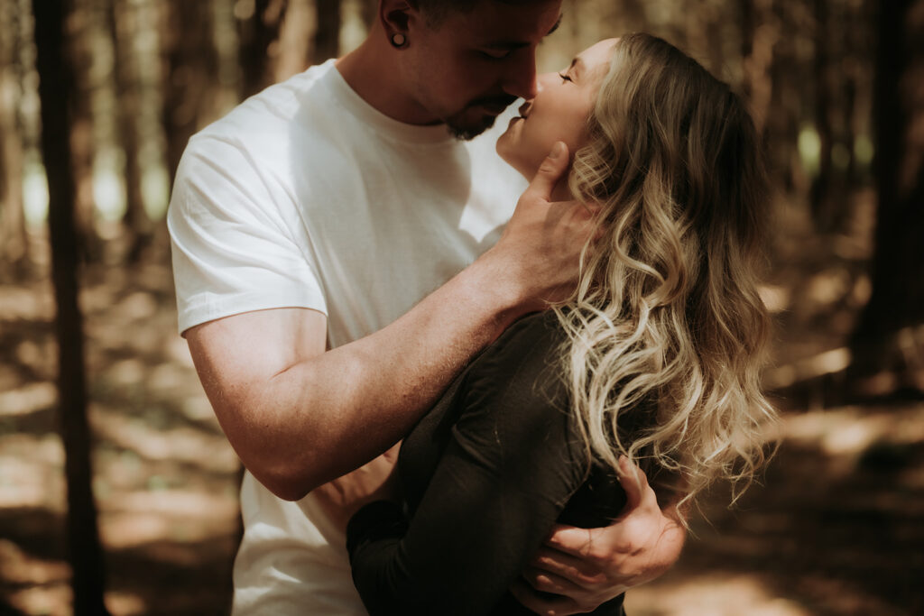 couple pose: man gently holds woman’s face and kisses her.