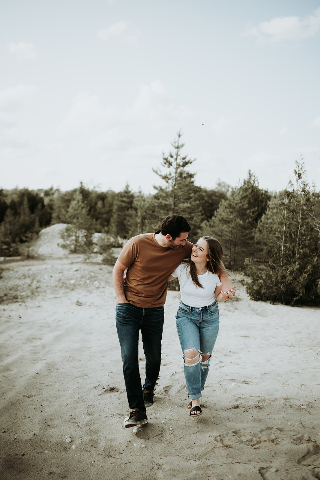 couple pose: a man snuggles close to the woman while walking looking at each other