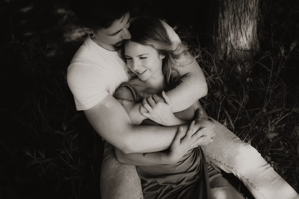 couple pose: one partner sitting comfortably between the other’s legs, snuggling closely.