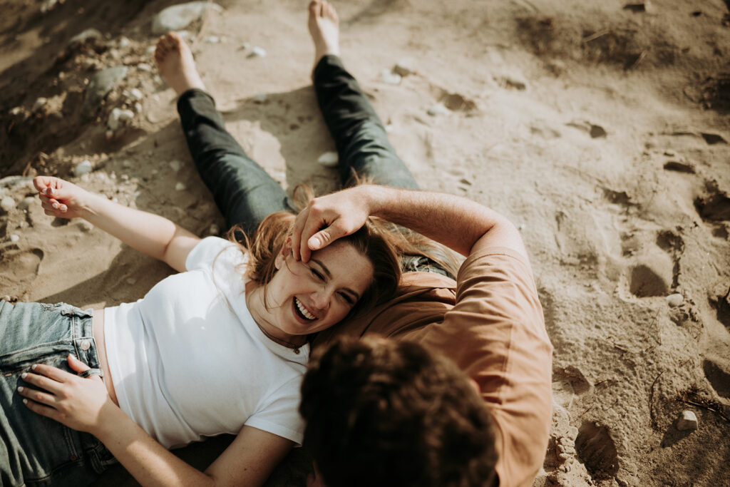 couple pose: woman is laying on a man's lap while the man strokes her hair.