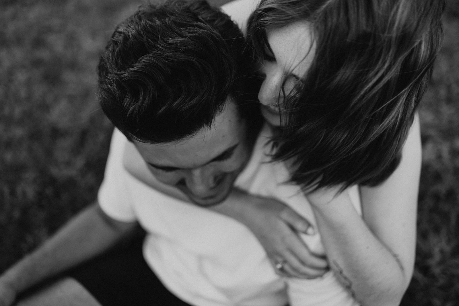 couple pose: a woman hugging a man from behind while playfully saying something on his ears.