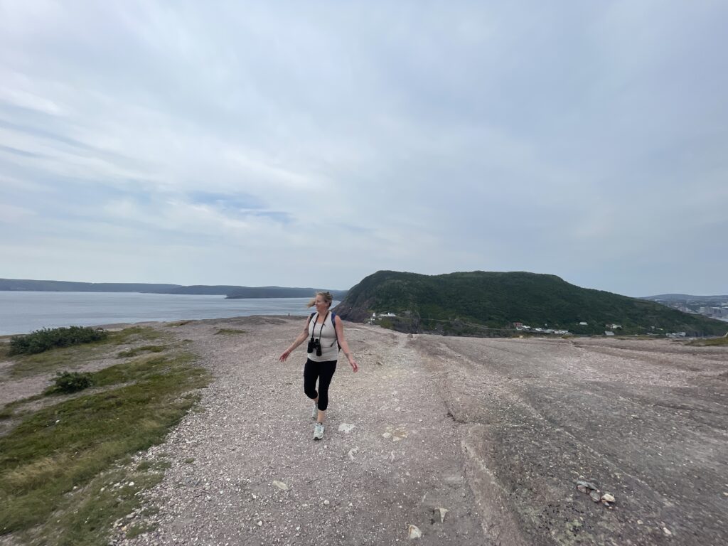 Rocky and narrow section of Signal Hill trail with cliffs and ocean views, children hiking with adult supervision.

