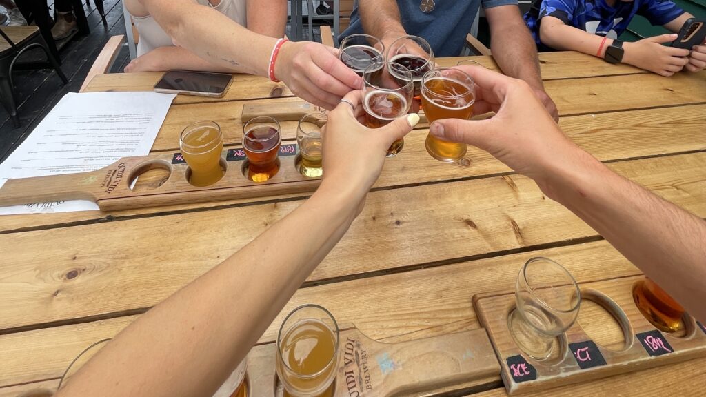 View of Quidi Vidi Brewery with harbor in the background, craft beer flights and outdoor seating on a sunny afternoon.